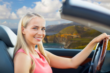 travel, road trip and people concept - happy young woman driving convertible car over big sur coast...