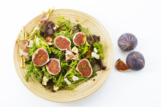 gemischter Blattsalat mit Feigen, Tomaten, Schafskaese und Crossinis mit Schinken auf Holzteller, Freisteller