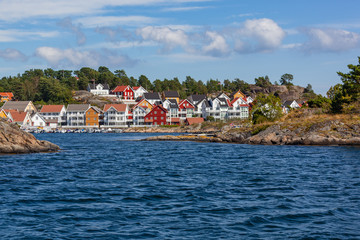 Fototapeta na wymiar The traditional coastal wooden houses covered in sunlight in the Lyngor archipelago, Southern Norway