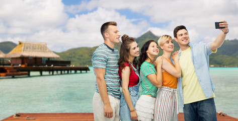 travel, tourism and technology concept - group of happy smiling friends taking selfie by smartphone...