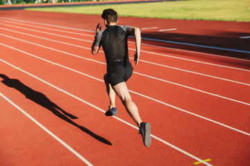 Back view of motivated young sportsman running