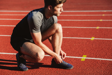 Concentrated young sportsman tying shoelaces