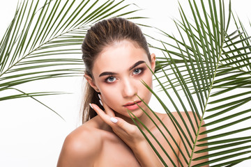 Portrait of young beautiful woman with a palm leaf, clean skin, Skin care concept.