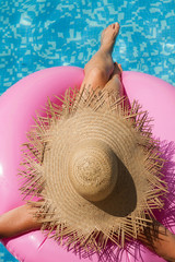 Mujer en la piscina sentada sobre un flamingo rosa con sombrero. Vista superior