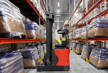 logistic business, shipment and loading concept - male loader operating forklift at warehouse © Syda Productions