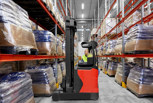 logistic business, shipment and loading concept - male loader operating forklift at warehouse