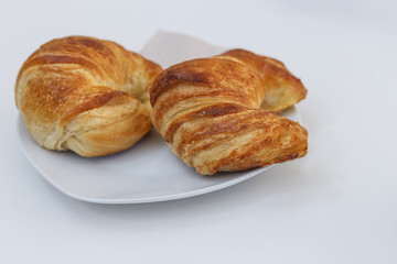 two fresh croissants on a plate on a light background as a food background