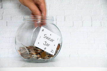 Glass Jar on a white shelf in a household living room. Swear box Concept