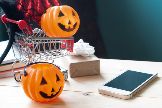 Halloween props and accessories on shopping cart with mobile phone on table