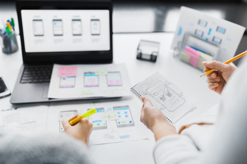 app design, technology and business concept - web designers working on user interface project and drawing sketch in notebook at office