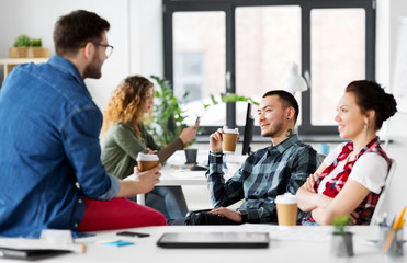 business and people concept - happy creative team drinking coffee at office