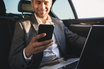 Smiling businessman holding mobile phone