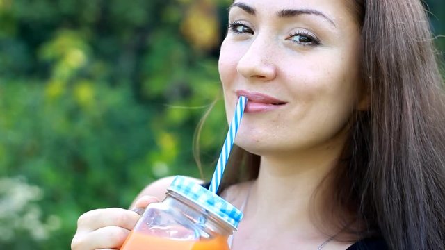 Woman drinks smoothies or orange fresh outdoors.