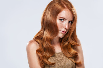 Naklejka premium Red head girl with long and shiny wavy hair. Beauty. Beautiful model woman with curly ginger hairstyle and frackles.