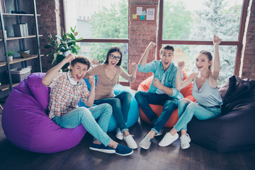 Group of carefree, joyful, crazy, emotional youngster looking into the camera raising their fists...