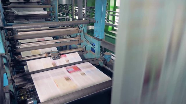 Machine works in printing office, close up. Newspaper printing equipment working.