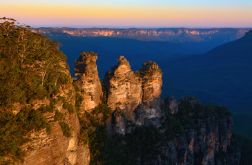 Orange glow of sunset on the peaks of the Three Sisters landmark in the Blue Mountains of Australia