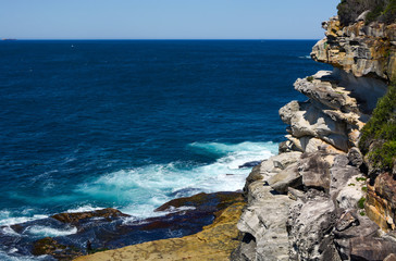 Rocky sandstone cliffs along the jagged coast of Lady Bay in South Head, NSW, Australia