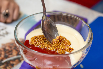 hands of people picking up spoons sauce from ketchup mayonnaise and mustard