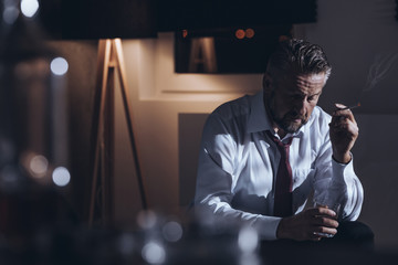 Depressed workaholic smoking cigarette