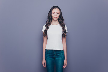 Attractive pretty adorable minded stylish curly-haired girl in jeans and t-shirt, isolated over grey background