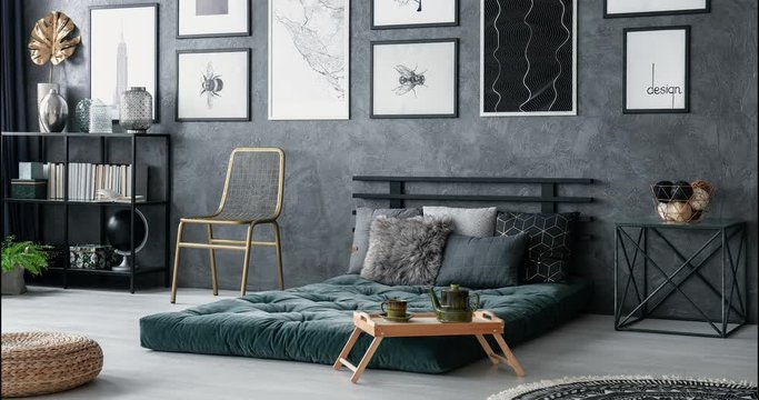 Stop-motion sequence of bedroom interior design. Video of cushions on green mattress and metal bedside table against gray, concrete wall.