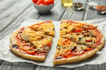 Sliced tasty pizza on parchment, closeup