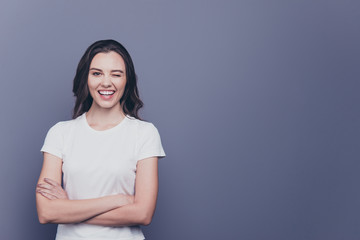 Obraz premium Adorable attractive nice charming gorgeous curly-haired brunette caucasian smiling winking young girl with folded hands. Copy space. Isolated over grey background