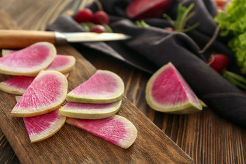 Wooden board with sliced radish on table, closeup