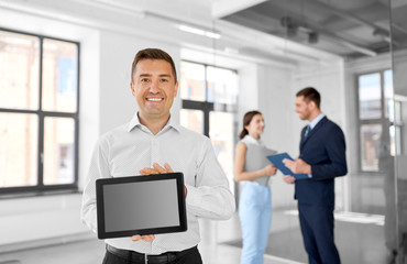 Naklejka premium real estate business, sale and people concept - happy smiling realtor or businessman showing tablet pc computer screen and customers at new office room