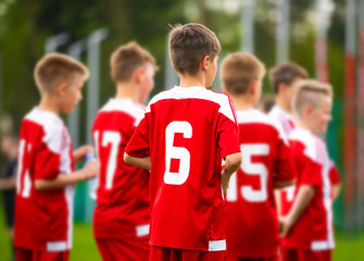 Fototapeta premium Drużyna piłkarska chłopców razem. Młodzi piłkarze w czerwonej koszulce sportowej