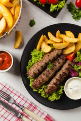 Traditional cevapcici served with baked potatoes. Flat lay. Stone background.