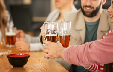Group of cheerful friends drinking beer in bar