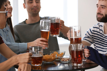 Group of friends clinking glasses with beer in bar