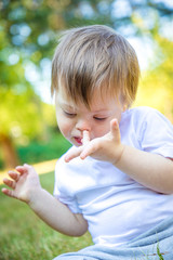 Portrait of Cute small boy with Down syndrome playing in summer day on nature