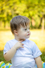 Portrait of Cute small boy with Down syndrome playing on blanket in summer day on nature