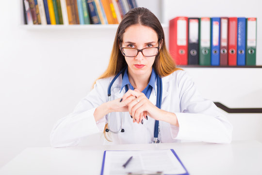 Young Female Doctor In Uniform In Doctor's Ofice Writting A Document