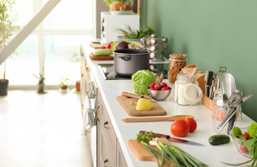 Cooking utensils with fresh vegetables on table in modern kitchen