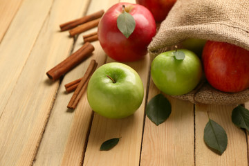 Fresh ripe apples and cinnamon on wooden background