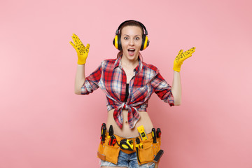 Handyman woman in plaid shirt, denim shorts, yellow gloves, noise insulated headphones, kit tools...