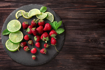 Ripe red strawberries with lime slices on slate plate