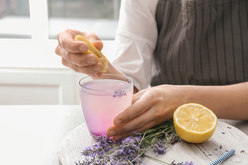 Young woman preparing lavender lemonade at table, closeup