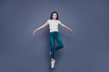 Graceful attractive adorable pretty stylish trendy nice lovely cheerful curly-haired brunette girl in casual white t-shirt and jeans, raising up in air, isolated on grey background