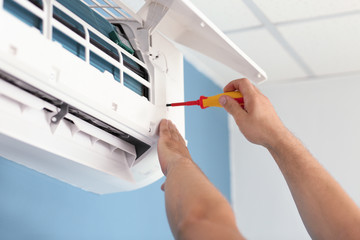 Electrician repairing air conditioner indoors, closeup