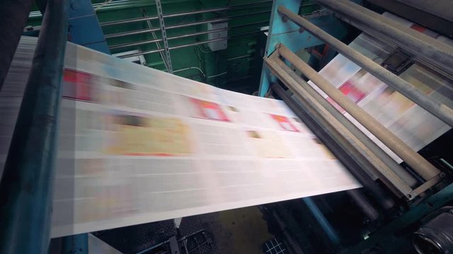 Newspaper printing at a plant, close up. Newspaper printed on a printing house machine.