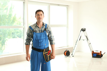 Electrician with tools in new empty apartment