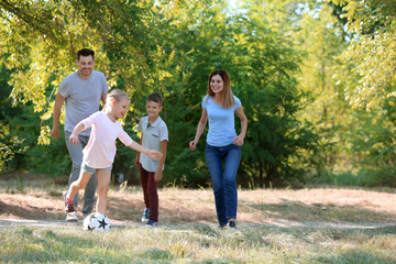 Happy family playing football outdoors