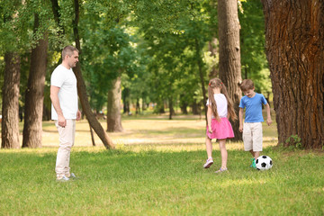 Obraz premium Happy family playing football in park on summer day
