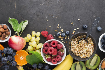 Ingredients for healthy breakfast meals: raspberries, blueberries, nuts, orange, bananas, grapes blue, green, apples, kiwi. Top View.