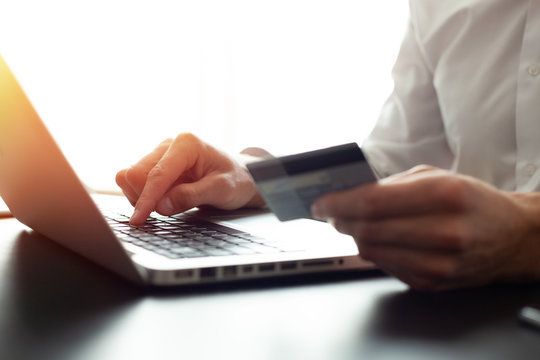 Hands holding credit card and using laptop. Online shopping.